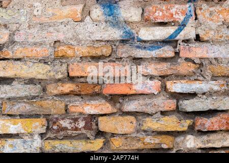 Un muro di mattoni rossi con un dashin blu nella città vecchia di Vilnius, Lituania. Tessitura di muratura vecchia. Vista ravvicinata Foto Stock