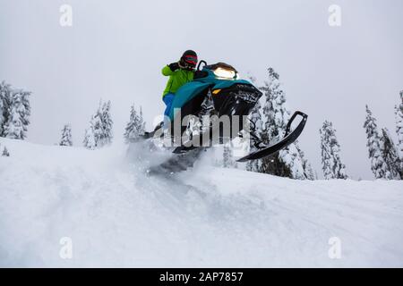 Uomo avventuroso in sella ad una motoslitta nel bianco della neve Foto Stock