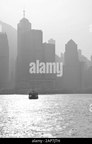 Immagine in bianco e nero dell'attraversamento dello Star Ferry tra il quartiere Centrale e la Penisola di Kowloon con una smog che pende sul centro di Hong Kong. Foto Stock