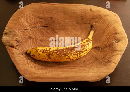 Una ciotola intagliata a mano di legno di noce che contiene una banana matura al suo interno. Foto Stock