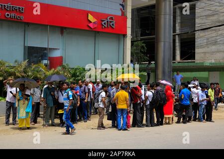 I pendolari aspettano un autobus urbano a Dhaka, in Bangladesh. Foto Stock