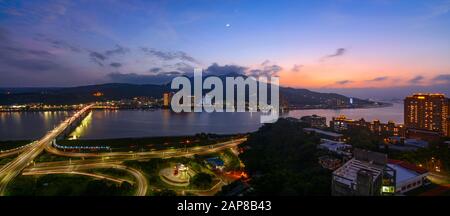 Panorama dei quartieri di Tamsui e Bali lungo il fiume nella città di New Taipei al tramonto con una luna crescente e il pianeta Venere che si innalza sopra Foto Stock