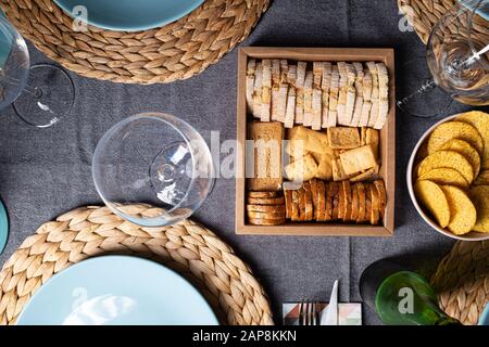 Diverse fette di pane tostato su una scatola di legno su un tavolo da pranzo ristorante preparato in blu e grigio Foto Stock