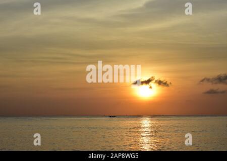 Alba sul mare vicino Amed a Bali con piccole sagome di barche locali lontano sulla superficie dell'oceano. Foto Stock