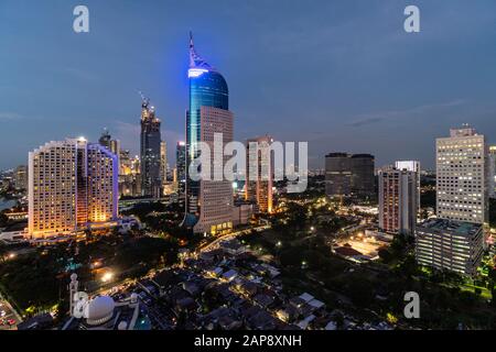 Incredibile crepuscolo sul centro di Giacarta distirct skyline, che contrasta con le basse case, nella capitale dell'Indonesia Foto Stock