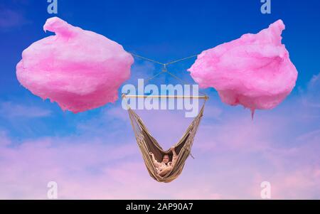 Amaca di cotone caramella nube. Giovane ragazza si rilassa in un'amaca tra due nuvole fatte di caramelle di cotone. Composizione dell'immagine concettuale illustrativa. Foto Stock