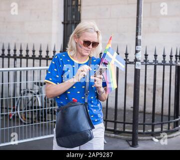 29 Giugno 2019, Parigi, Francia. Giornata Parata Gay Pride. Bella close up scatto di una donna nei suoi anni cinquanta guardando il suo telefono. Ha vernice arcobaleno sopra Foto Stock