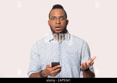 Sorpreso uomo nero confuso dal messaggio inatteso sullo smartphone Foto Stock