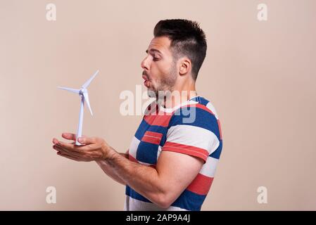 Ritratto di uomo che soffia modello di turbina eolica Foto Stock