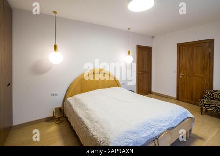 Interni luminosi e moderni della camera da letto. Letto a scomparsa con schienale rotondo. Luci rotonde. Porte in legno. Foto Stock