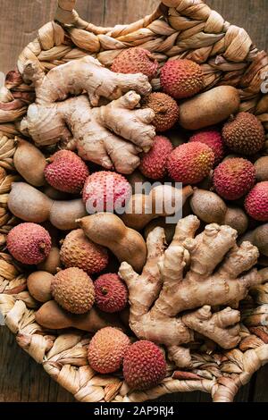 Lychee, tamarindo e radice di zenzero in un cestino di vimini, cibo tailandese. Foto Stock