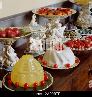 Vista ravvicinata di un tavolo pieno di frutta e dessert al servizio di dessert Minton, e stand per torte, 1850s nella pasticceria Pantry. Foto Stock