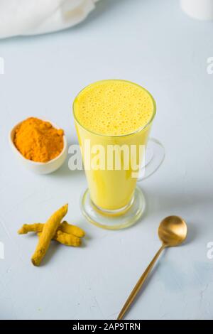 Bicchiere di latte curcuma dorato ayurvedico e curcuma. Bevanda detox naturale. Primo piano. Scatto verticale. Bevanda asiatica sana alla moda per immunità wi Foto Stock