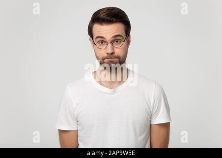 Millennial insoddisfatto serio bearded uomo in occhiali che stringono le labbra. Foto Stock