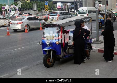 Bangkok, Thailandia - 21 dicembre 2019: Donne musulmane e ragazzo negoziare con tuk tuk autista per il trasporto. Foto Stock