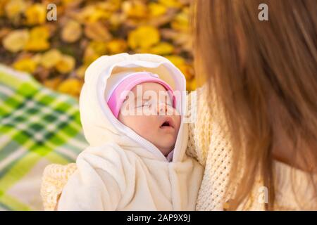 Il bambino di due mesi dorme nelle braccia della mamma Foto Stock