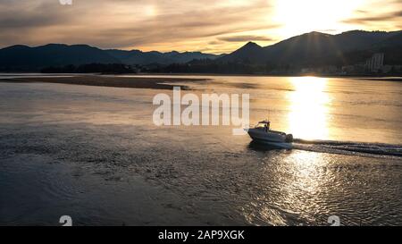 Barca ricreativa a Mundaca estuario al tramonto con Sukarrieta e montagne (Riserva della Biosfera di Urdaibai, Busturialdea, Biscay, Paesi Baschi, Spagna) Foto Stock