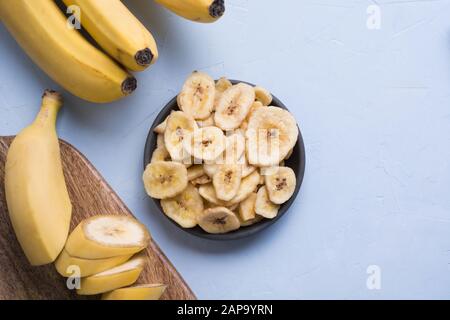 Disidratati, freschi e Banane essiccate chip nella ciotola nero su sfondo chiaro. Vista da sopra. Foto Stock