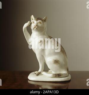 Una figura di un gatto di porcellana bianca seduto con una zampa sollevata alla sua testa. E 'stato fatto da Meissen c1741-1745 e si trova nella Mirror Room. Foto Stock