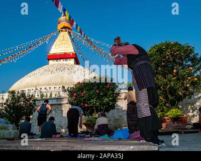 I pellegrini tibetani stanno praticando le prostrazioni a Boudha Stupa Foto Stock