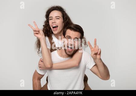 Giovane gioioso che dà piggyback millennial amata donna. Foto Stock