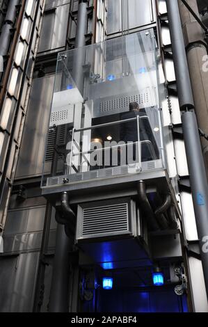 La gente viaggia negli ascensori presso il Lloyd's di Londra, in Lime Street, Londra, Inghilterra Foto Stock