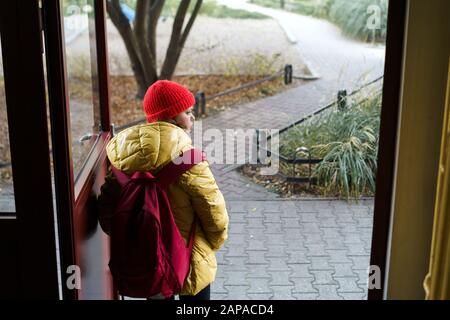 Ragazza scolaretta di 12 anni che lascia la casa con uno zaino che apre la porta Foto Stock