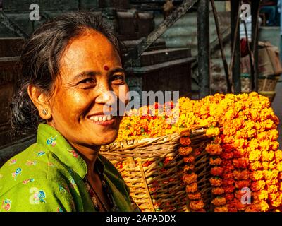 Donna locale che vende fiori marigold gialli per rituali religiosi nei mercati di strada della città Foto Stock