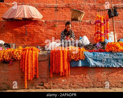 Donna locale che produce e vende fiori per rituali religiosi nei mercati di strada della città Foto Stock