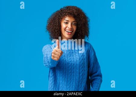 Girovita-up ritratto allegro soddisfatto africano americano femmina con taglio di capelli afro, estendere braccio e mostrare pollice-in su in approvazione, felice buon risultato, per esempio Foto Stock