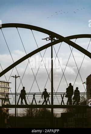 Il Manchester Curve Bridge a Piccadilly Place a Manchester, pieno di pendolari e pedoni Foto Stock