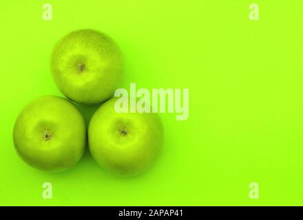 tre mele verdi su sfondo verde, immagine monocromatica Foto Stock