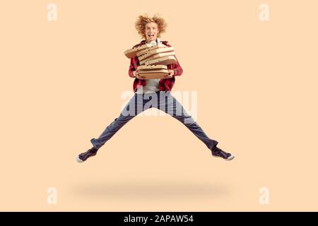 Ragazzo giovane adulto che salta in su con le scatole della pizza del cartone Foto Stock