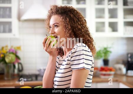 Donna che prende un morso grande di una mela Foto Stock