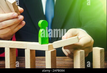 Un uomo d'affari costruisce un percorso per una figura verde. Fare un percorso verso il successo, il sostegno e l'assistenza finanziaria. Costruire un business e un'azienda. Carriera gro Foto Stock