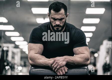 mente mentale sport motivazione concetto di giovane uomo forte con la barba che indossa la maglia nera concentrazione relax in palestra sport Foto Stock