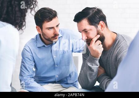 Capire le persone che danno sostegno all'uomo depresso durante la sessione di terapia di gruppo Foto Stock