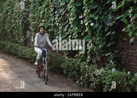 Le donne asiatiche indossano i caschi per guidare le bici pieghevoli Foto Stock