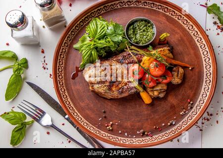 Entrecote di maiale servito con verdure alla griglia, funghi e salsa al pesto, piatto ristorante, vista dall'alto, orientamento Orizzontale Foto Stock