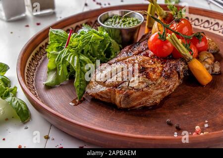 Entrecote di maiale servito con verdure alla griglia, funghi e salsa al pesto, piatto ristorante, orientamento Orizzontale Foto Stock