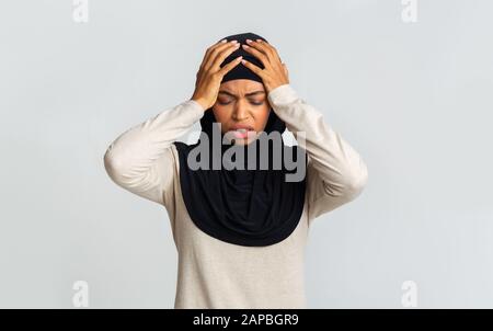 Malata donna musulmana nera in velo che tocca la testa con le mani Foto Stock