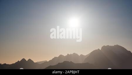 Sole splendere in serata nebbiosa vista cielo. Silhouette in montagna con nuvole. Clima, ambiente e meteo concetto cielo sfondo. Foto Stock