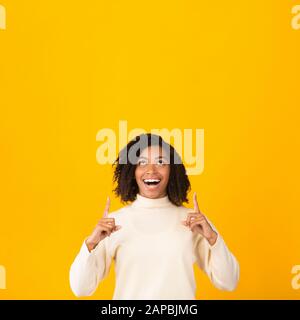 Donna afro sorridente che punta in su allo spazio vuoto Foto Stock