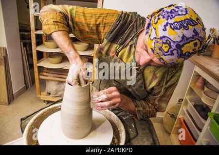 Vasaio maestro lavorando sulla ruota del vasaio, facendo nuova ciotola da argilla grezza Foto Stock