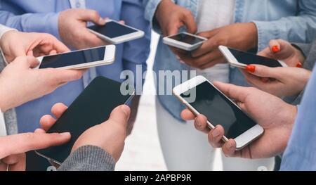 Primo piano di persone diverse in piedi in cerchio che tiene gli smartphone Foto Stock