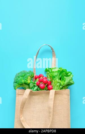 Verdure fresche in sacchetto di tessuto riutilizzabile su fondo blu. Foto Stock