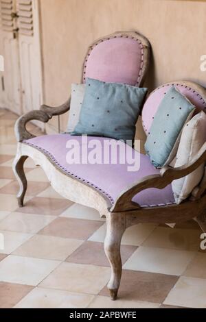 Tessile rosa in stile vintage divano con blu e grigio cuscini vicino che ricordano le pesche sfondo. Concetto interno. Foto Stock