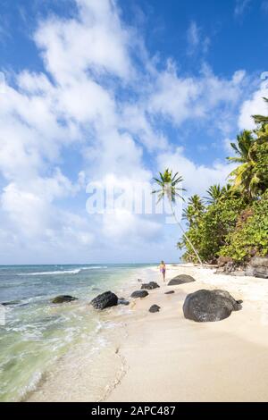 Una giovane donna che cammina lungo una spiaggia tropicale incontaminata ombreggiata con palme sulle remote Isole Corn del Nicaragua Foto Stock