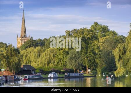 Vista sul fiume Avon fiancheggiata da alberi salici e la guglia della chiesa della Santissima Trinità (luogo di sepoltura di Shakespeare), Stratford-upon-Avon Foto Stock