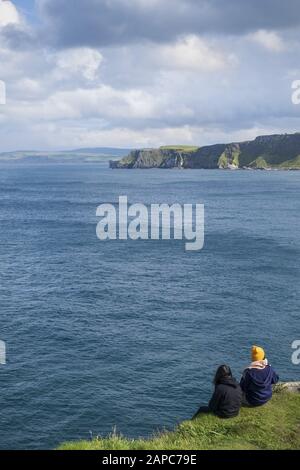 Gli escursionisti si fermandano per un riposo a Torr Head sulla strada rialzata della costa di Antrim e sulla strada costiera Foto Stock